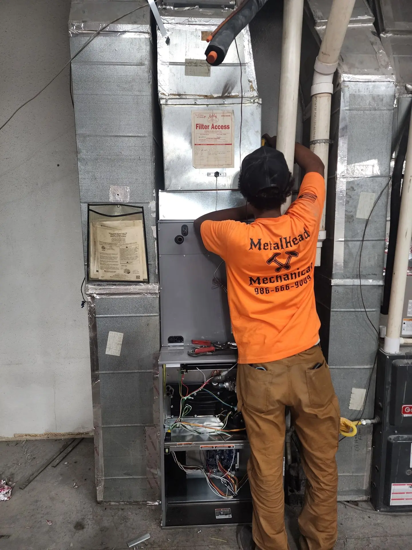 MetalHead technician in company shirt servicing an air handler
