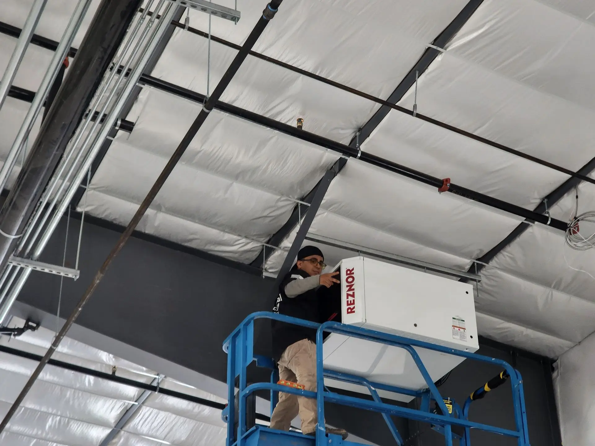 MetalHead technician installing a unit heater from a scissor lift