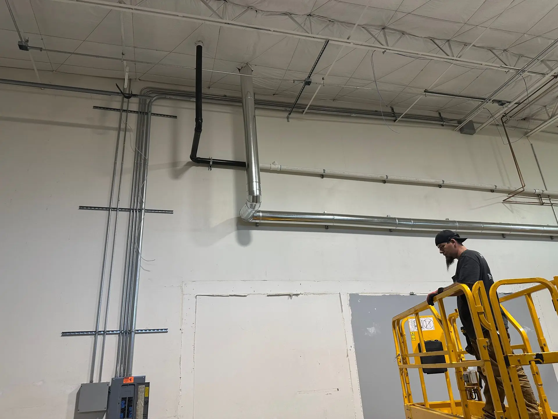 MetalHead technician on a scissor lift beside a new commercial flue run