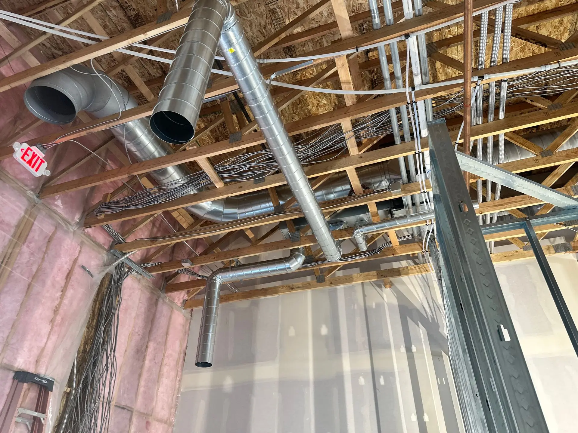 Spiral duct routed through wood trusses in a commercial build-out