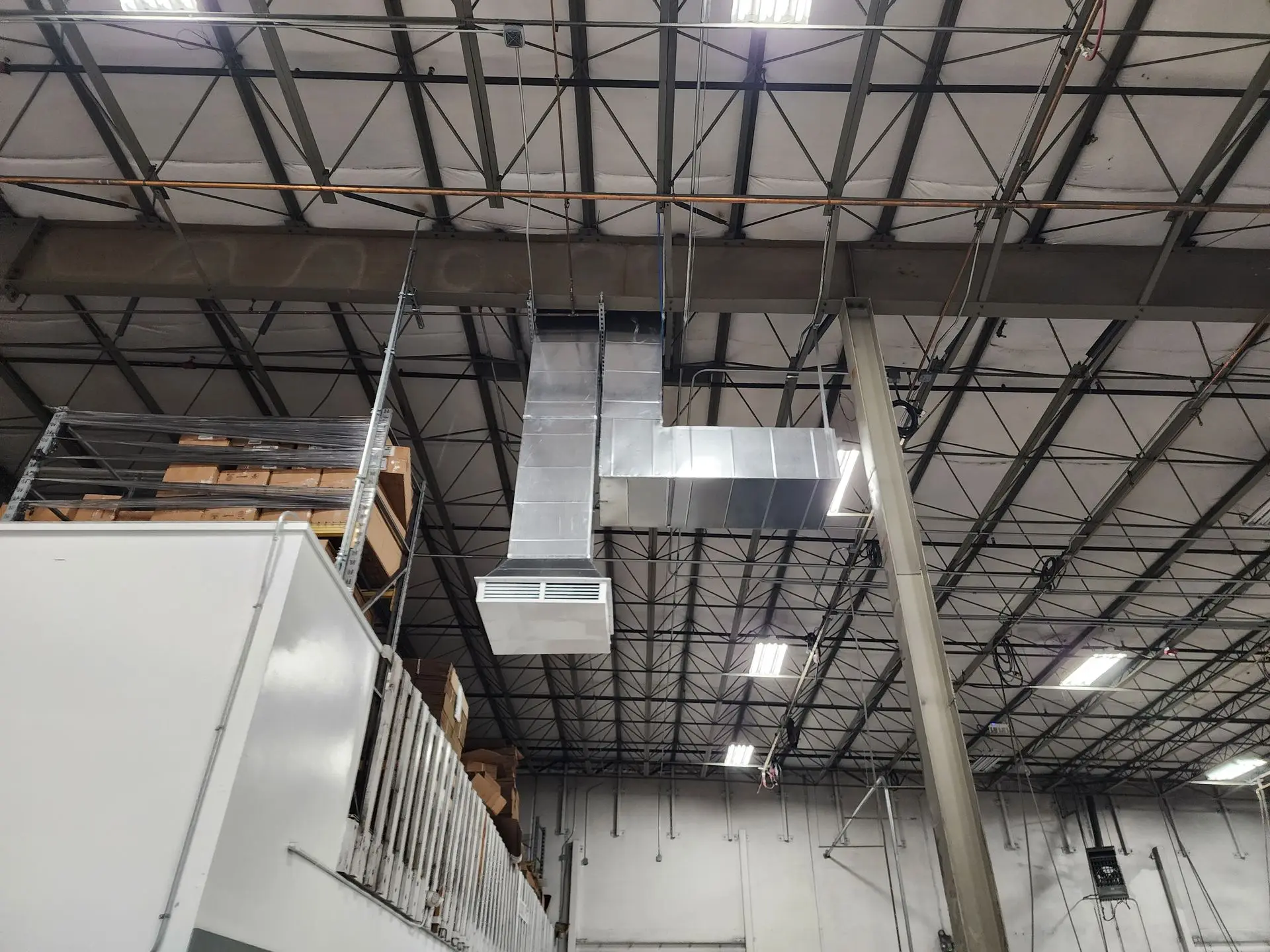 Custom rectangular duct with register hung from a warehouse ceiling