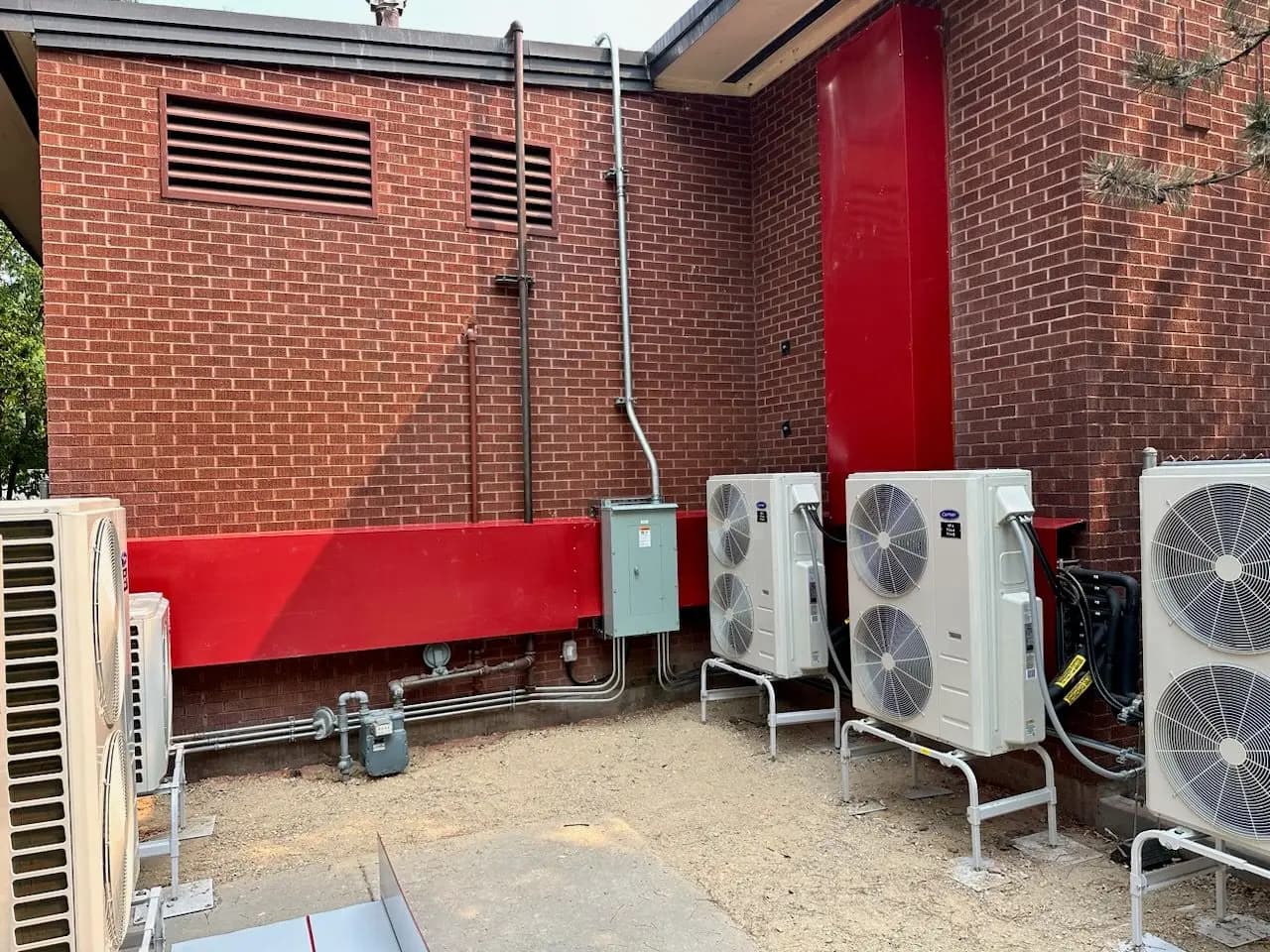 Bank of heat pumps installed against a brick commercial building