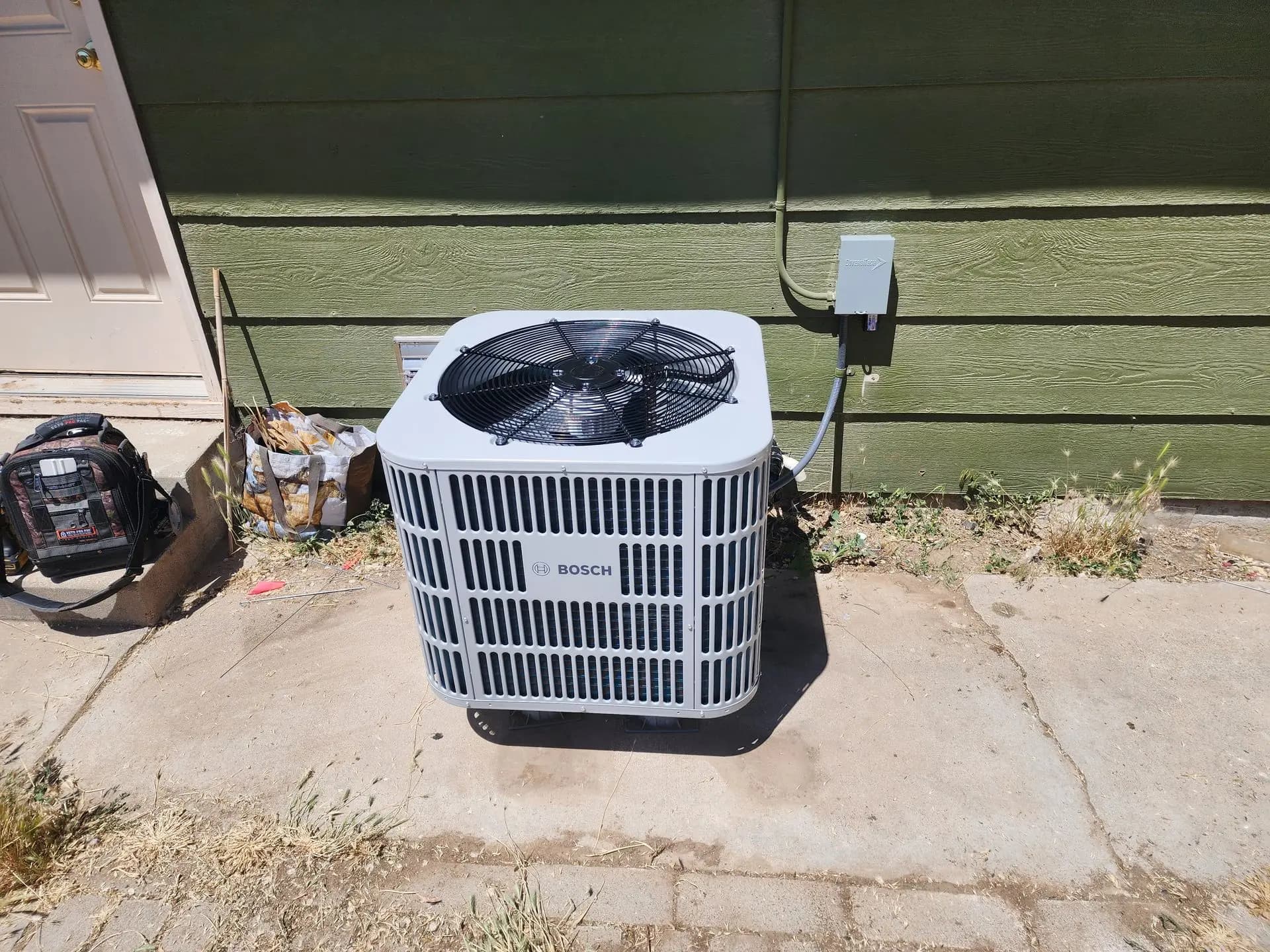 New Bosch heat pump condenser on a pad beside a house